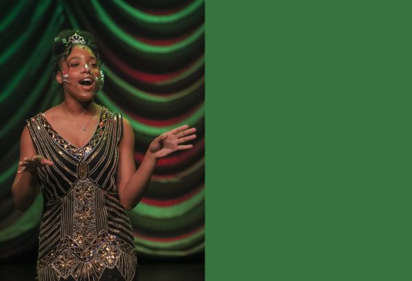  A student sings in front of a green and red curtain 